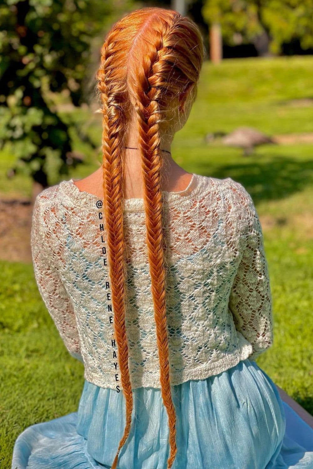 A red-haired woman with double fishtail braids hairstyle.