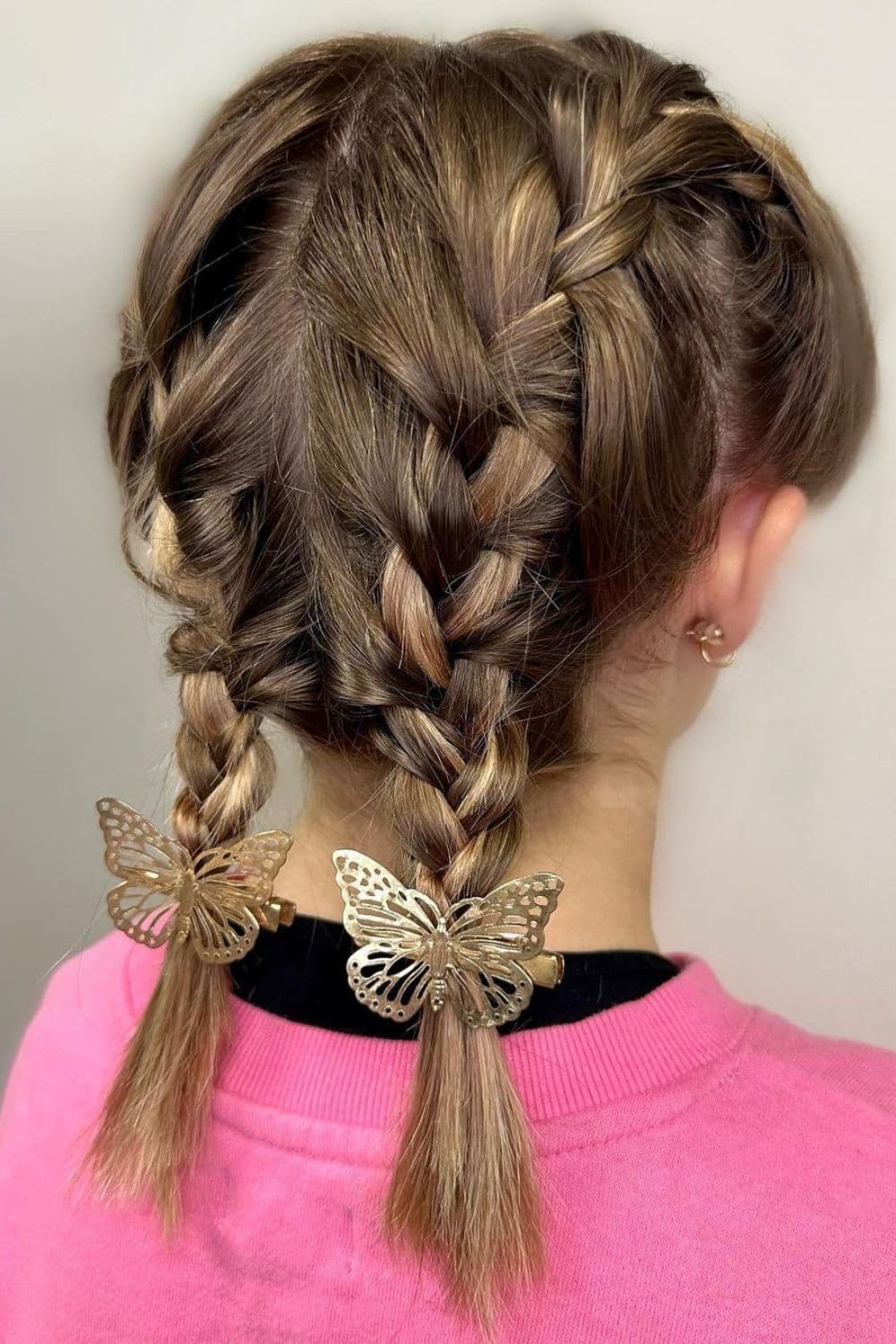 A girl with double French braids with two butterflies accessories.