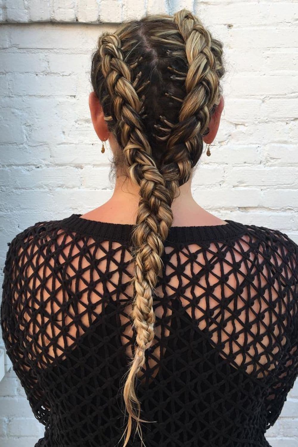 A woman with black and blonde double French braids into a single ponytail.