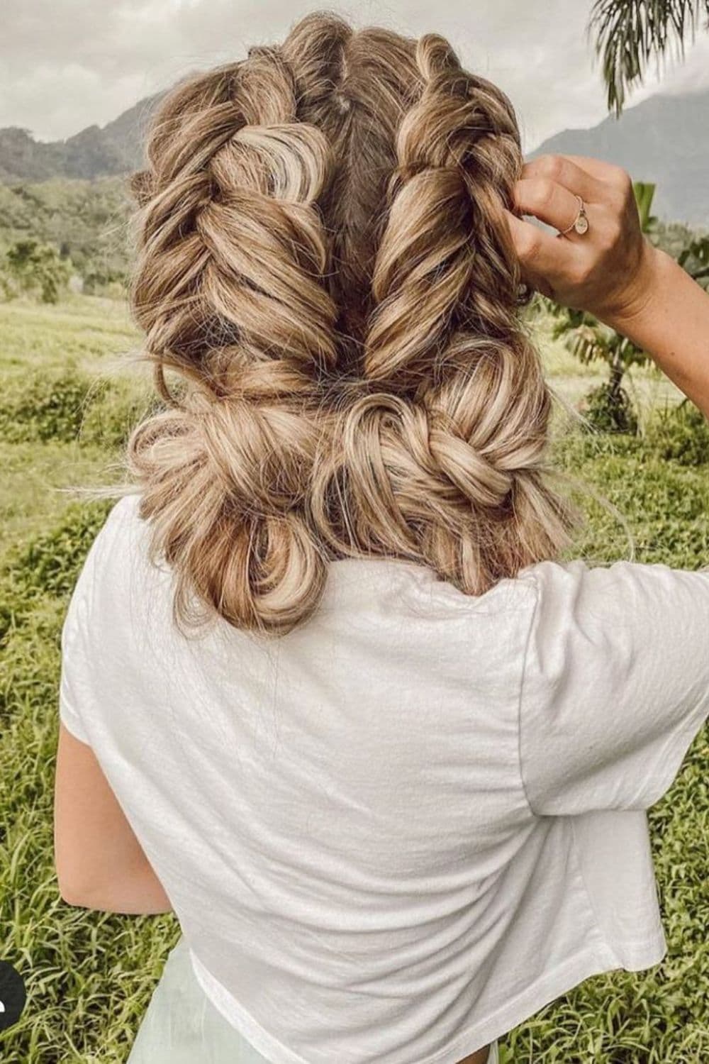 A woman with a blonde Dutch fishtail bun hairstyle.
