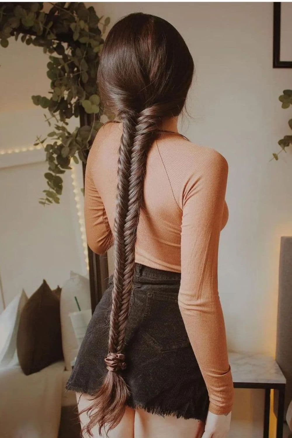 A woman standing with a black fishtail ponytail.