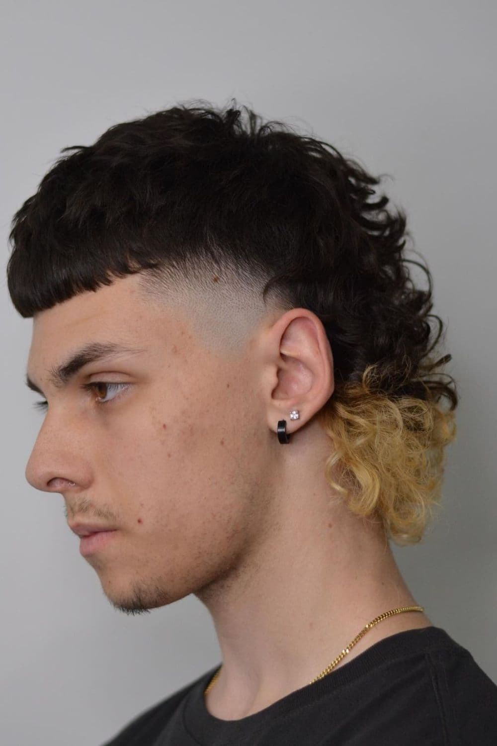 Side view of a man with ombre half-bowl curly mullet.