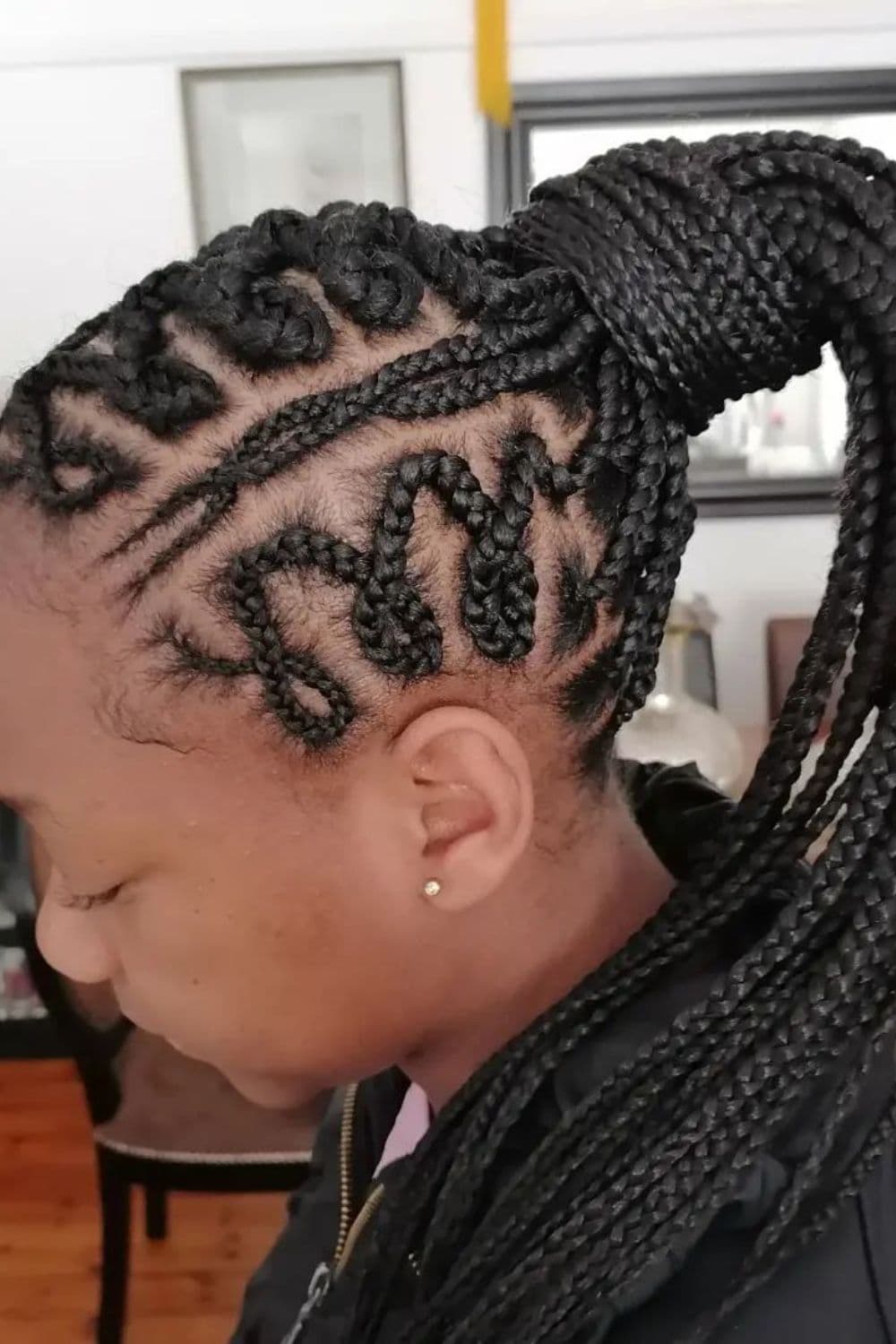 Side view of a woman with black half cornrows into a ponytail.