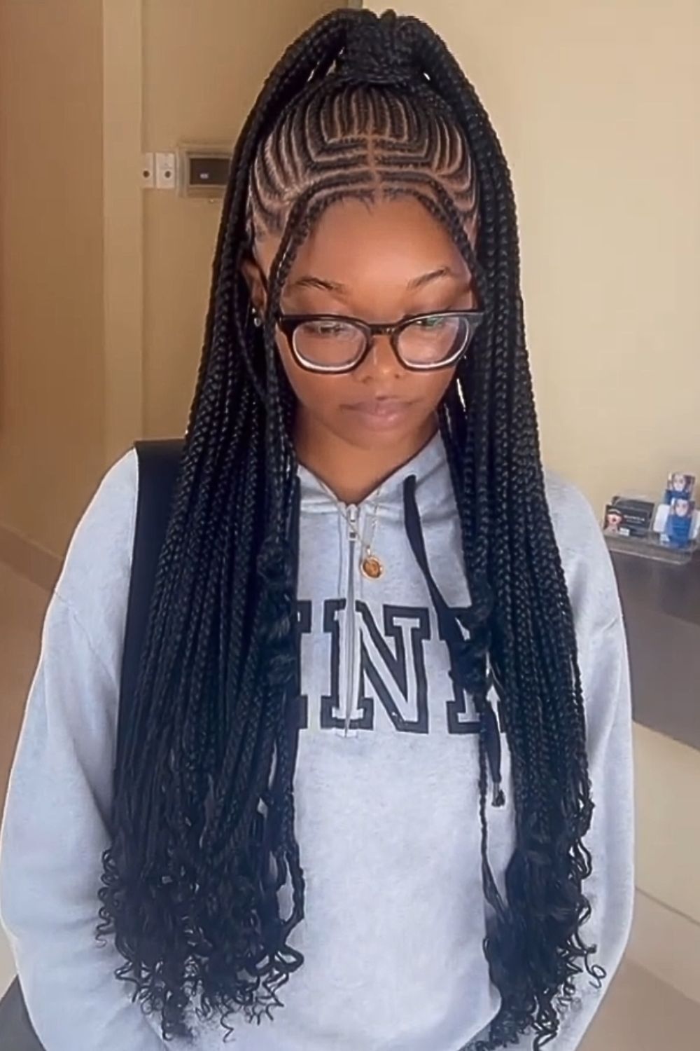 A woman wearing eyeglasses with half-up half-down middle-parted tribal braids.