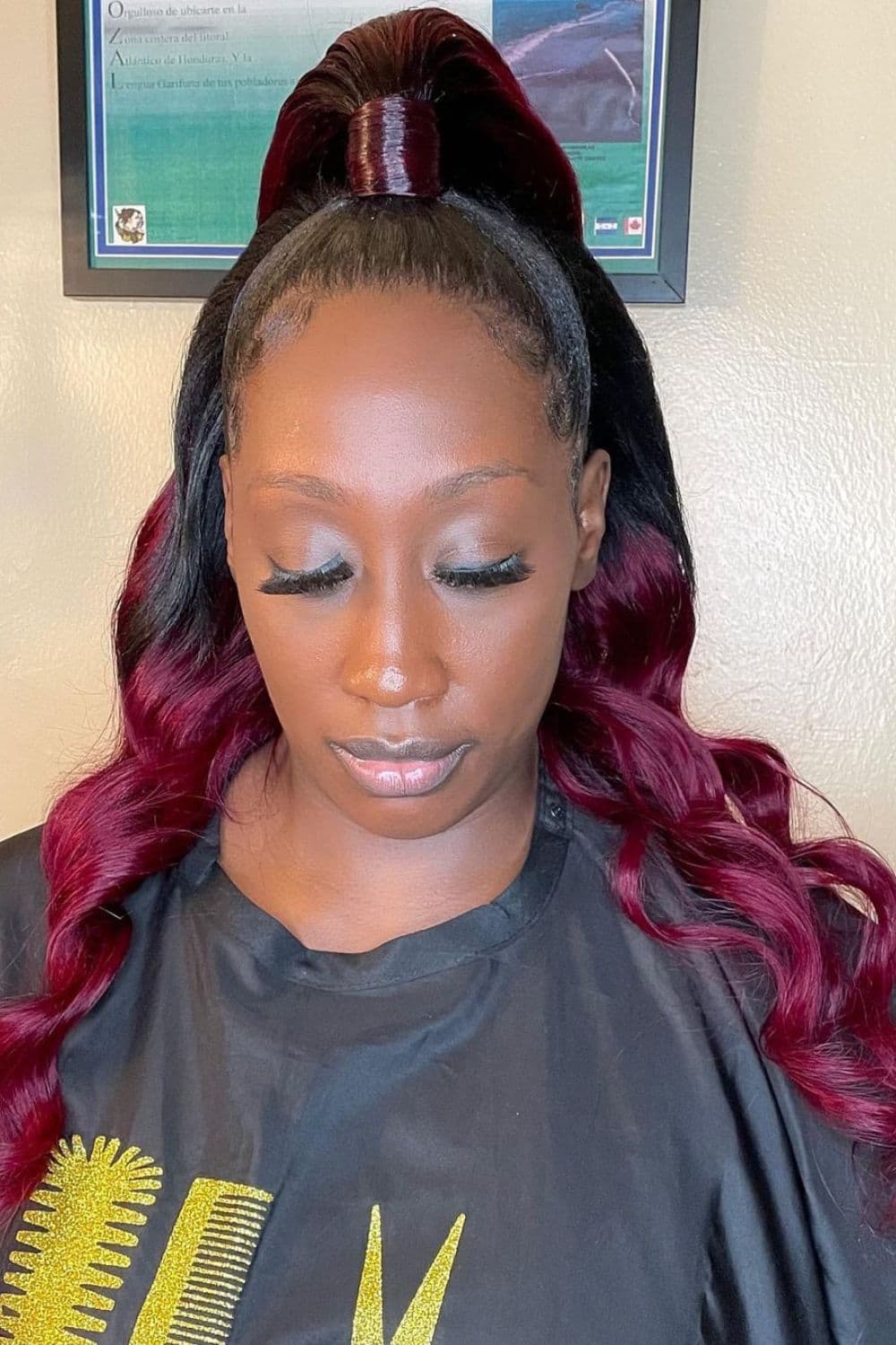 A woman with half up half down quick weave with red ends.