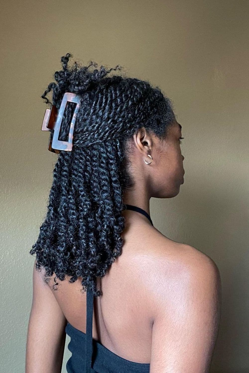 Side view of a woman with a half up half down two-strand twists.