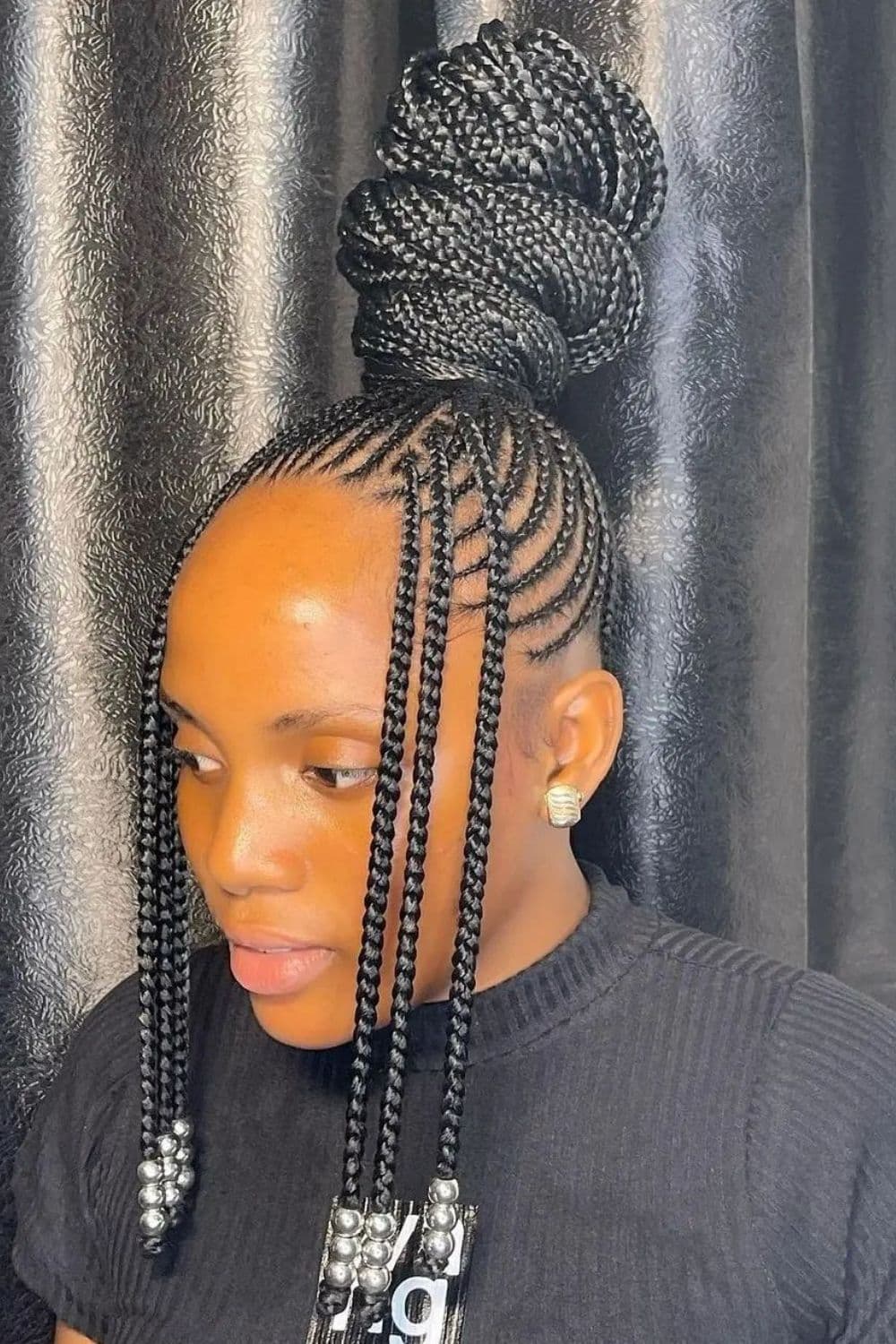 A woman with high bun box braids with beads.