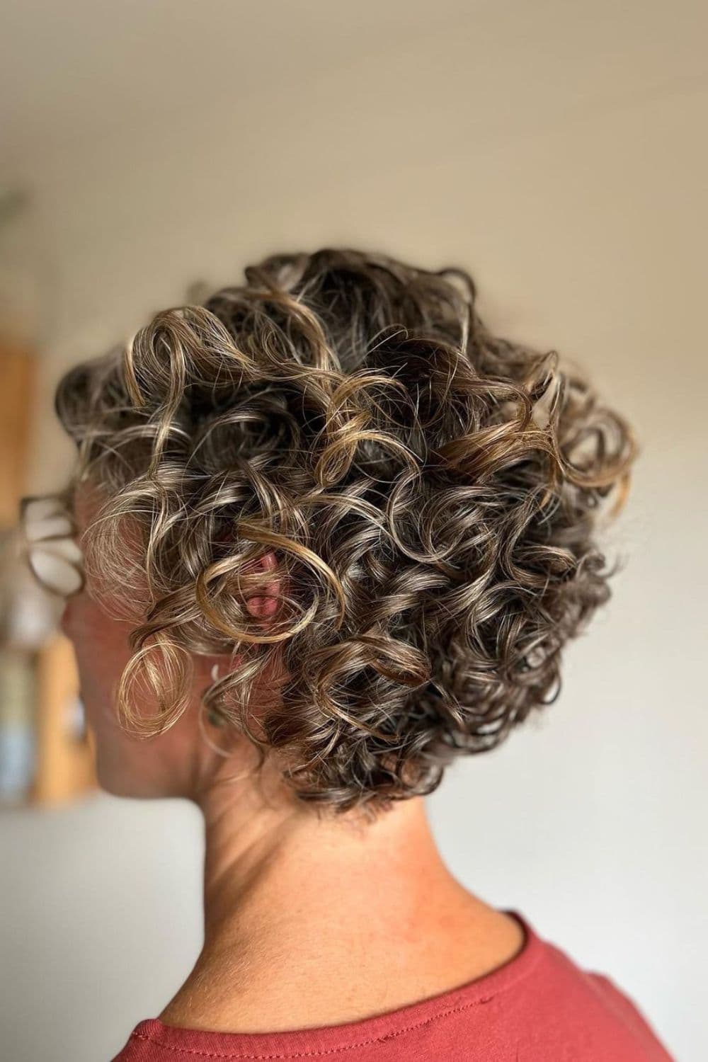 Side view of a woman with curly, inverse-layered lob.
