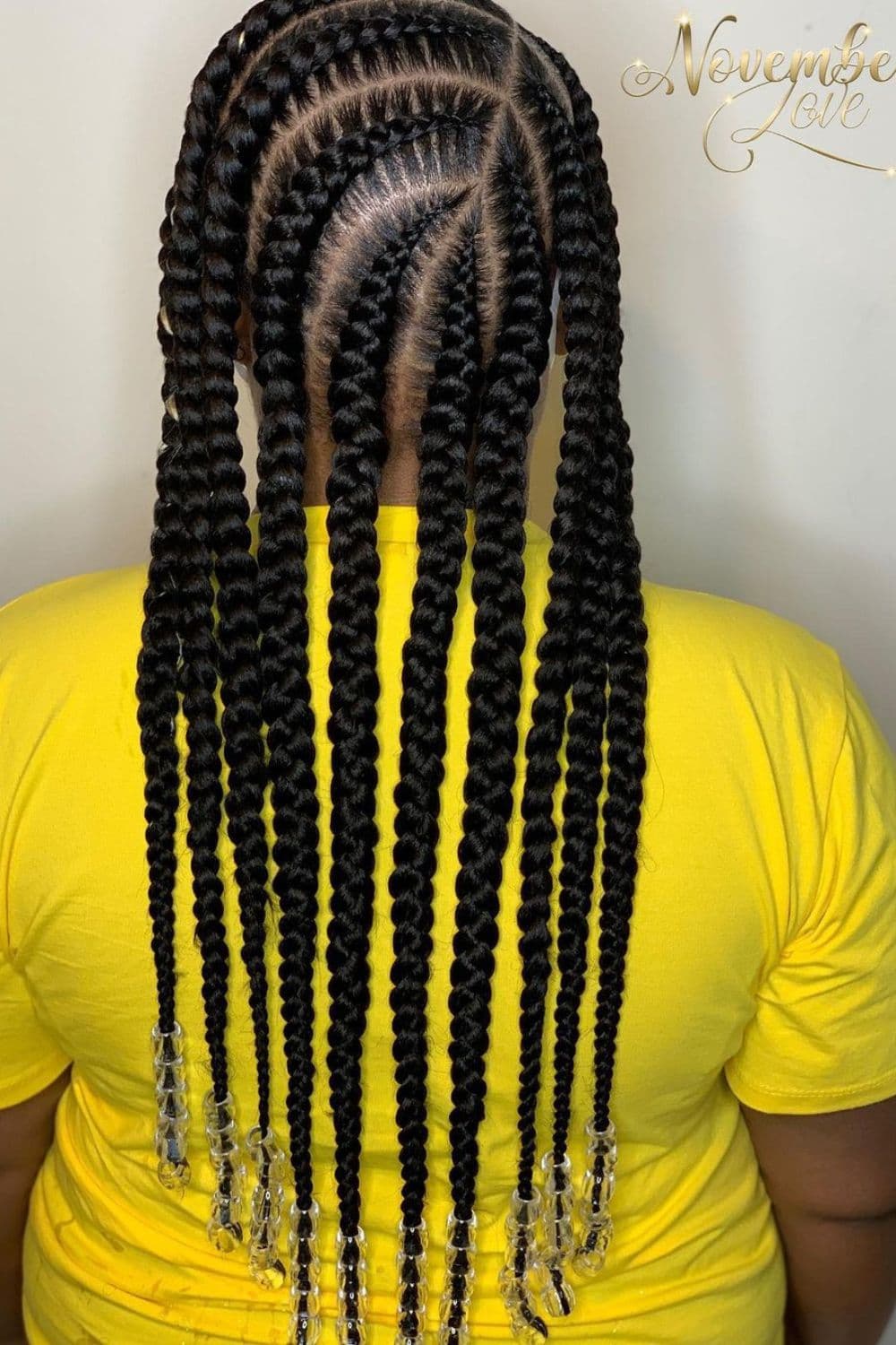 A woman wearing a yellow t-shirt with jumbo cornrows with beads.