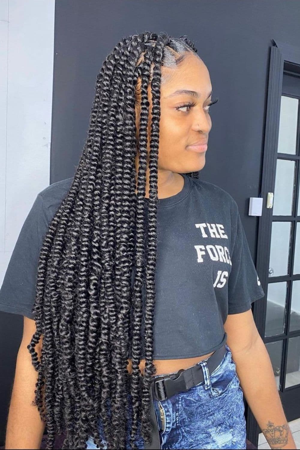 Side view of a woman wearing a black crop top with a black jumbo passion twists.