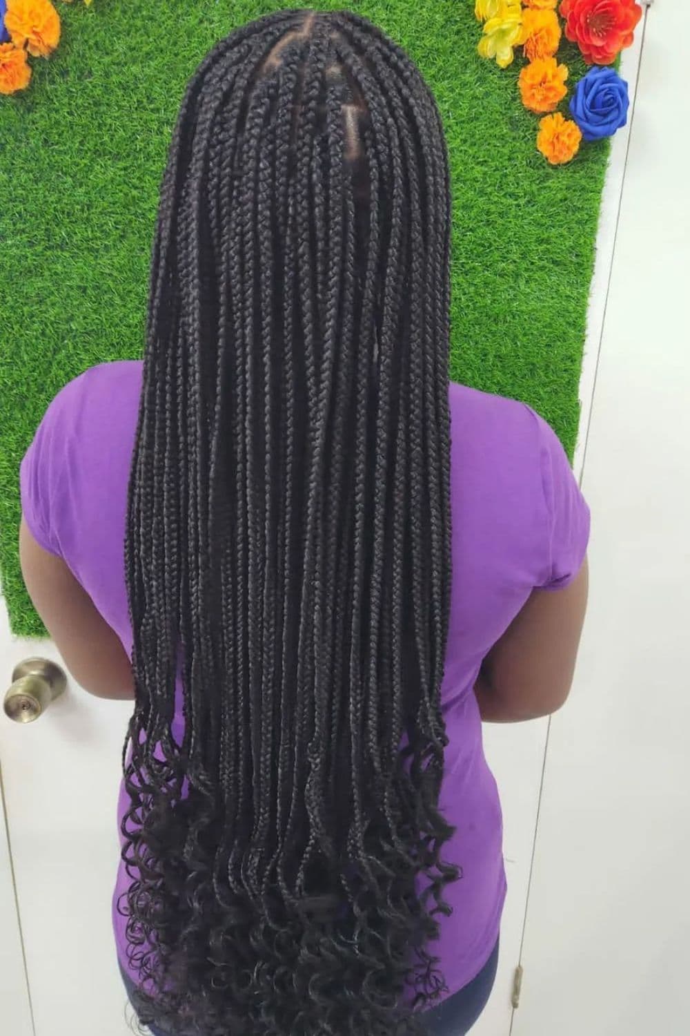 A woman in purple t-shirt with black knotless box braids with curly ends.