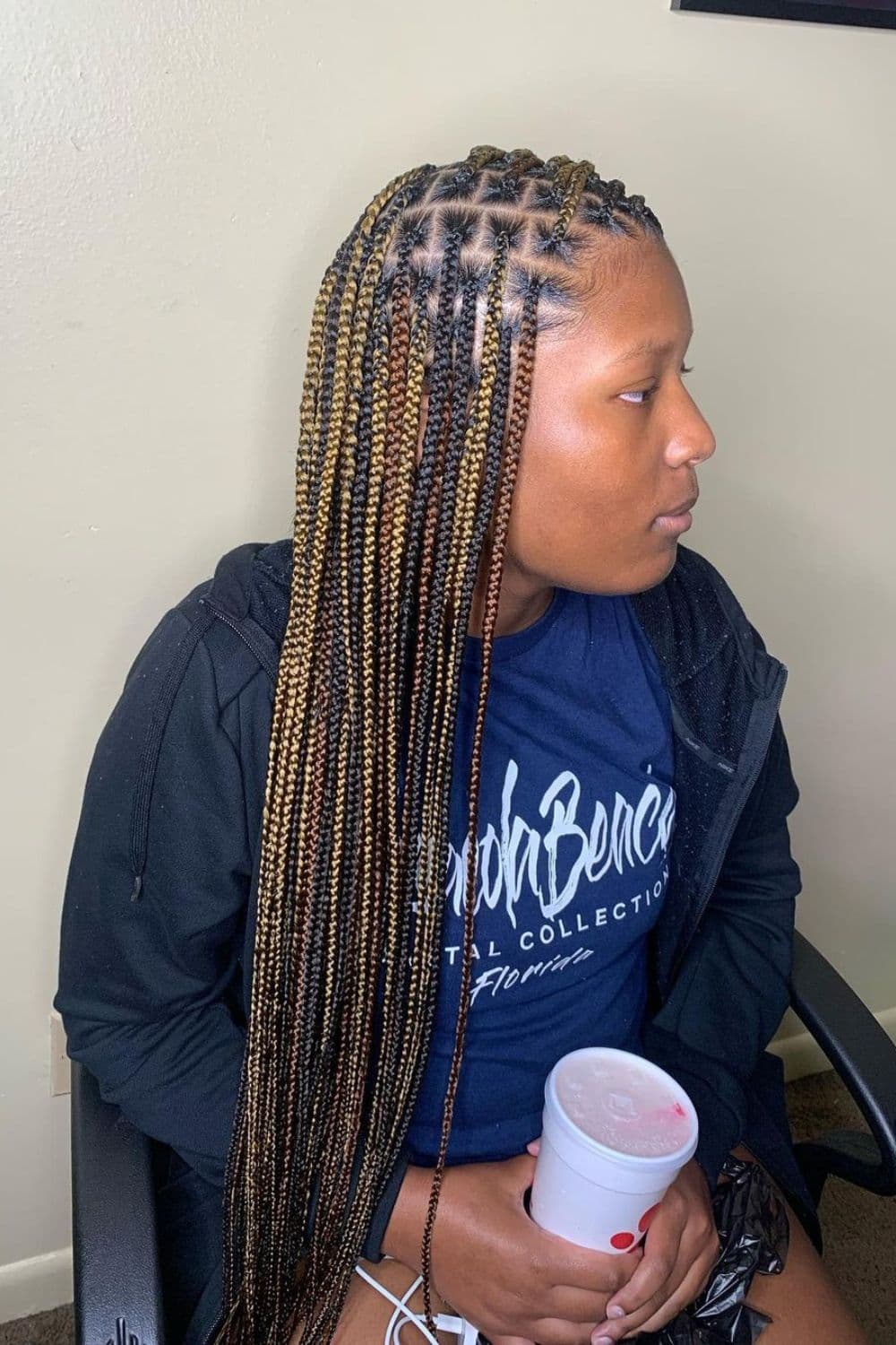 Side view of a woman with black, brown, and blonde knotless braids.
