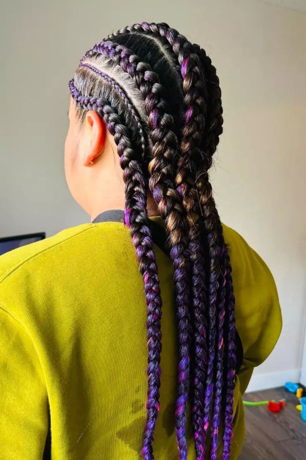Side view of a woman wearing a yellow sweatshirt with multicolor knotless cornrow braids.