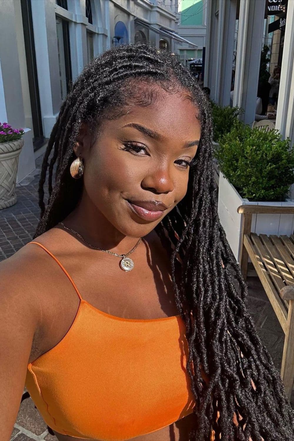 A woman wearing an orange crop top with a long comb twist.