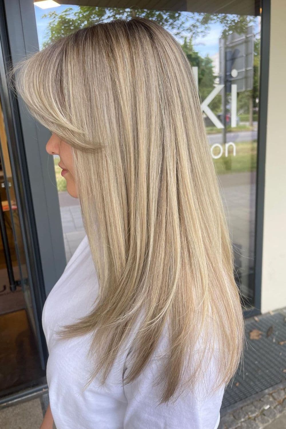 Side view of a woman with blonde, front layers with shadow root.