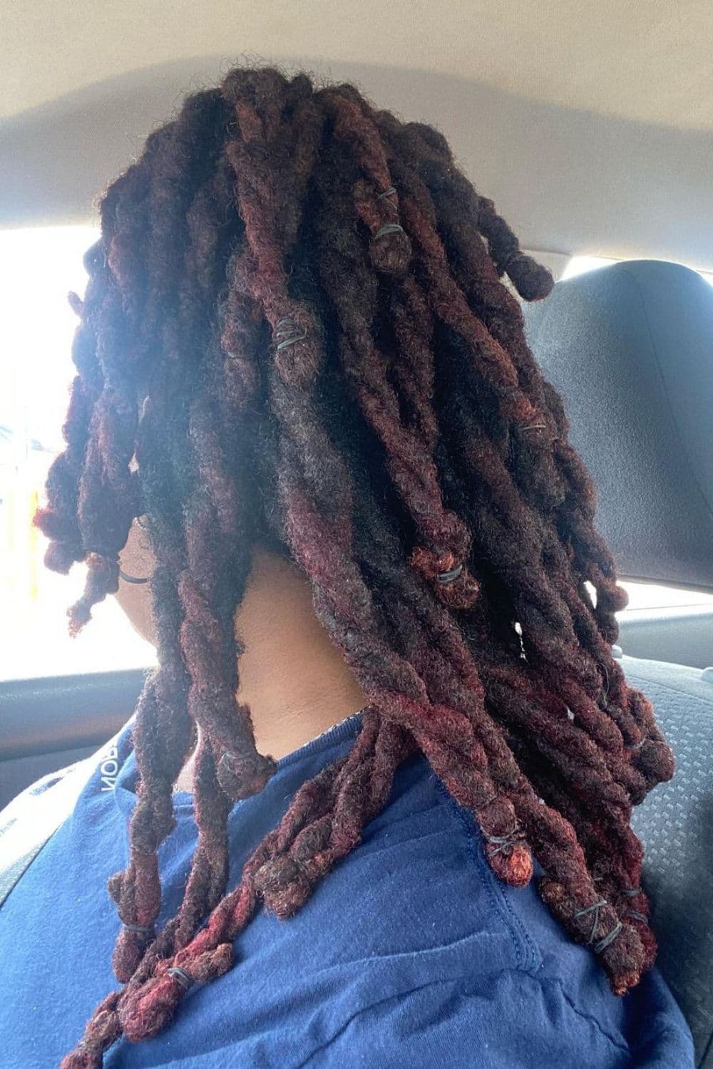 A woman sitting in a car with loose two-strand twists.