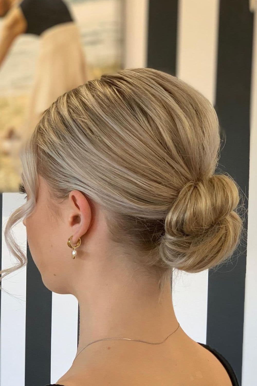 Side view of a woman with a blonde low ballerina bun.