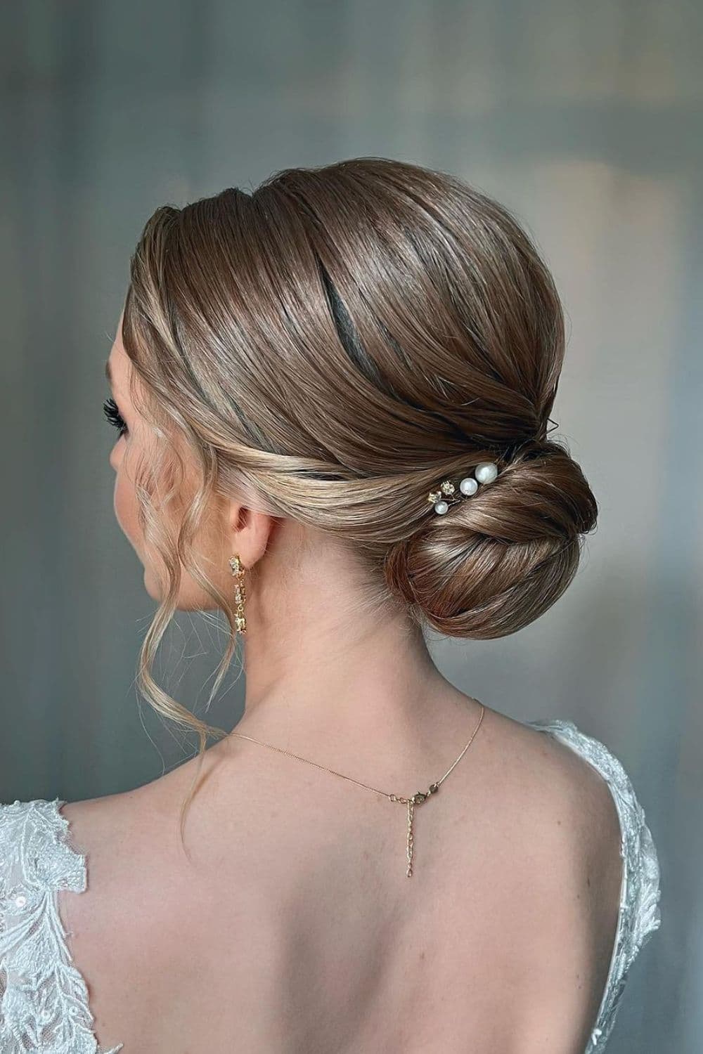 Side view of a woman with a blonde low bun with pearl accessories.