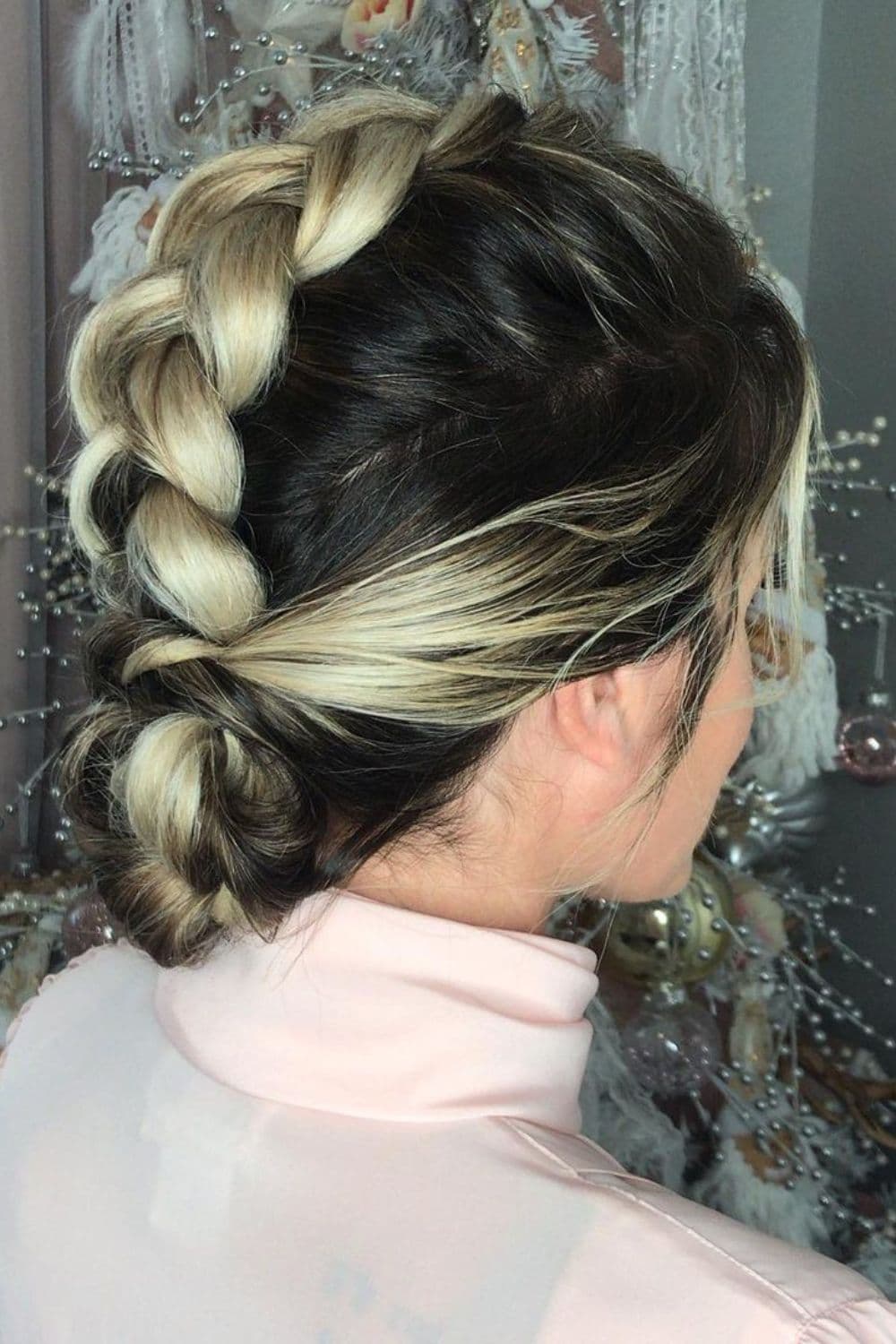 A woman with a black and blonde low bun with a mohawk braid.