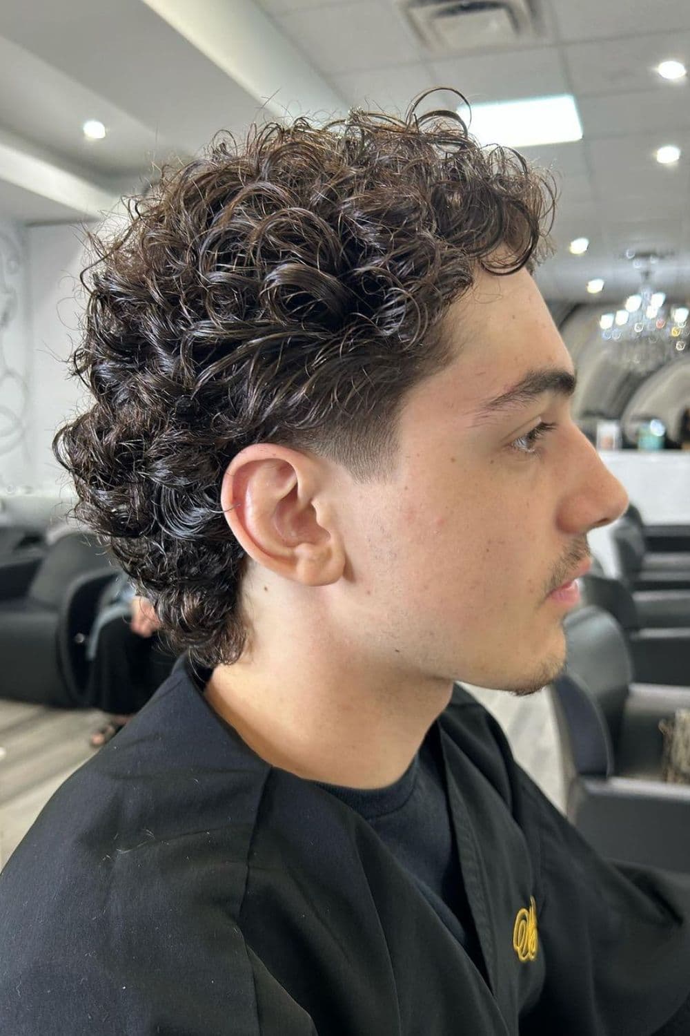 Side view of a man with low taper fade with curly hair.