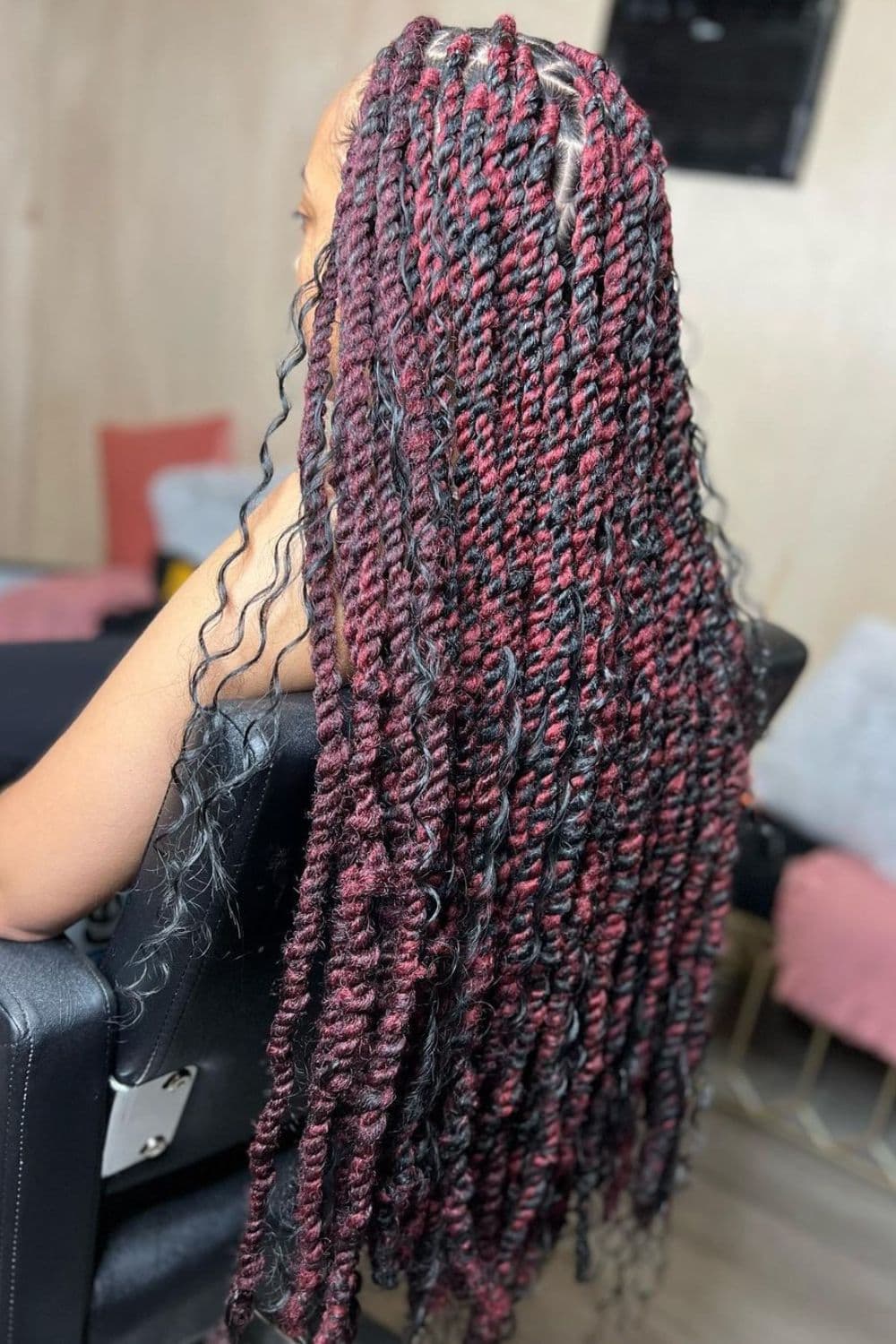 A woman sitting on a chair with black and burgundy Marley twists.