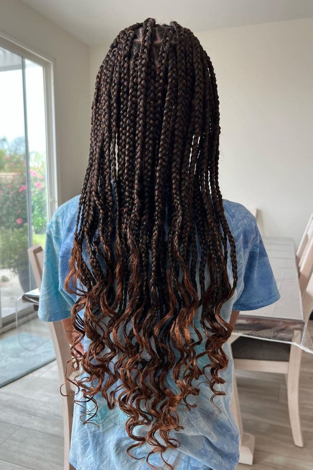 Back of a girl with medium box braids and curly ends.