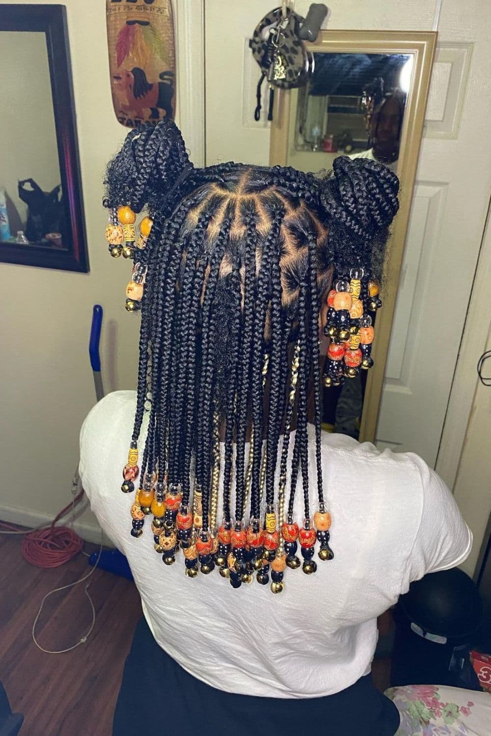 A person with medium box braids with golden beads.