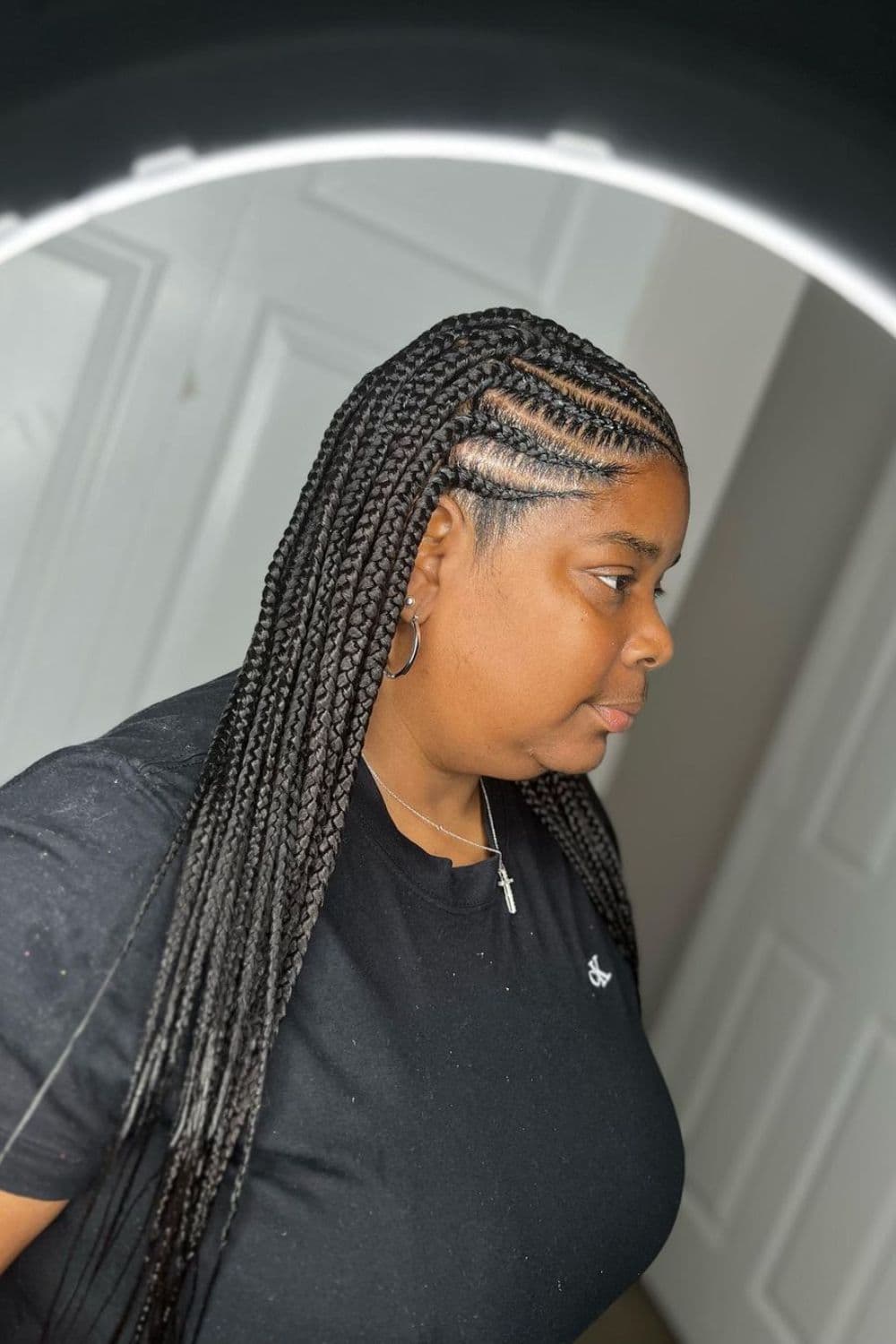 Side view of a woman with black medium Fulani braids with knotless box braids.