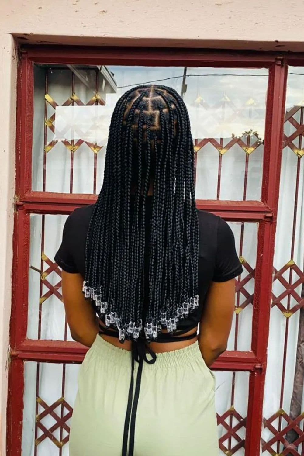 Back of a woman with black medium knotless braids with clear beads.