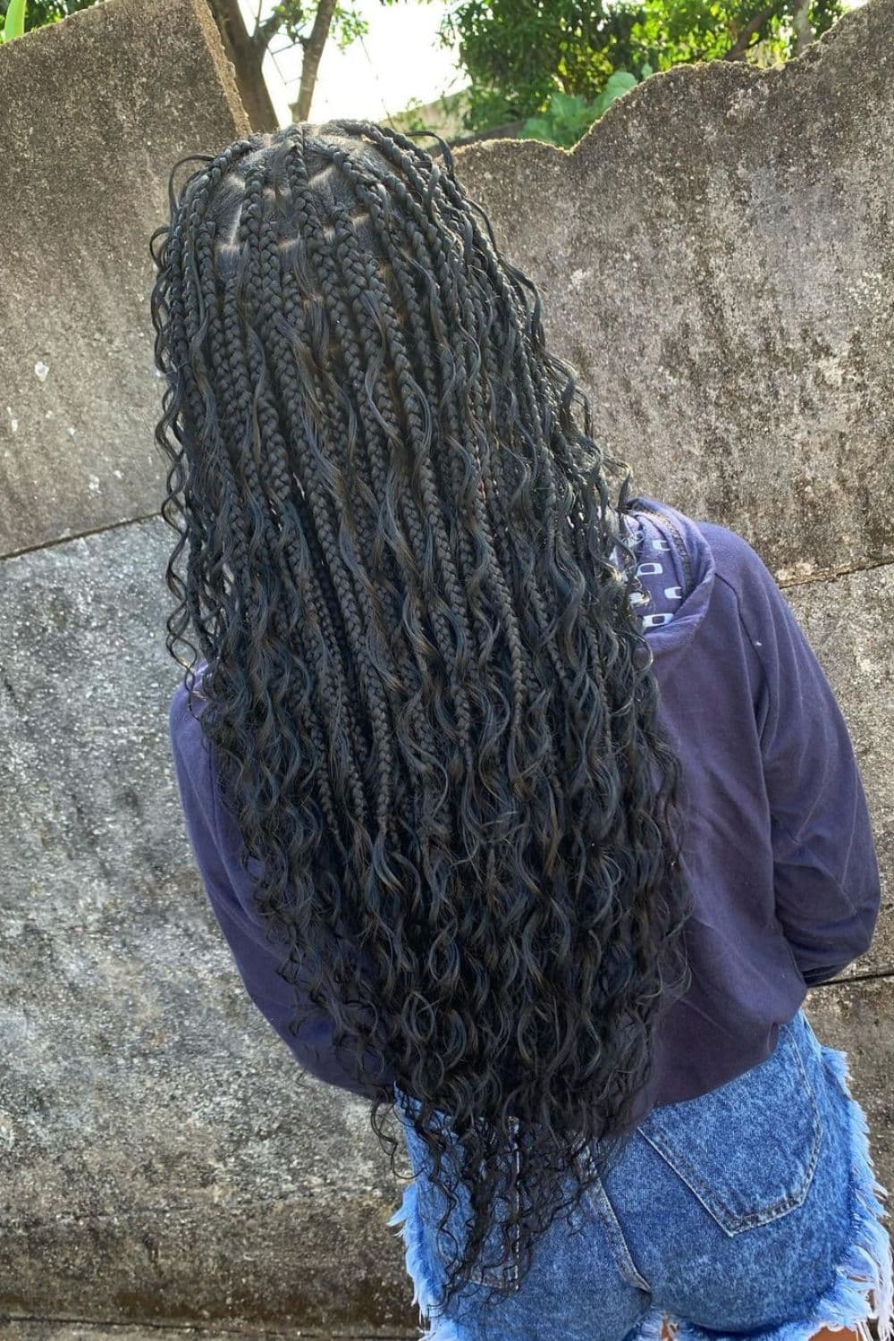 Back of a woman with black medium knotless goddess braids.