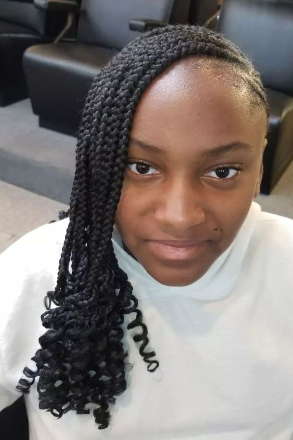 A woman wearing a white turtleneck with black medium lemonade braids with curly ends.