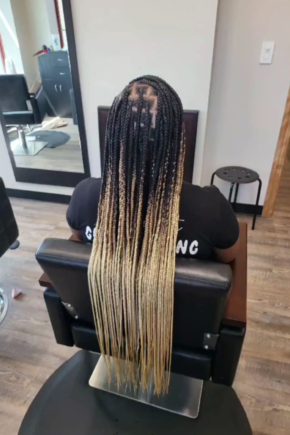 A woman sitting in a hair salon with medium mixed blonde knotless braids.