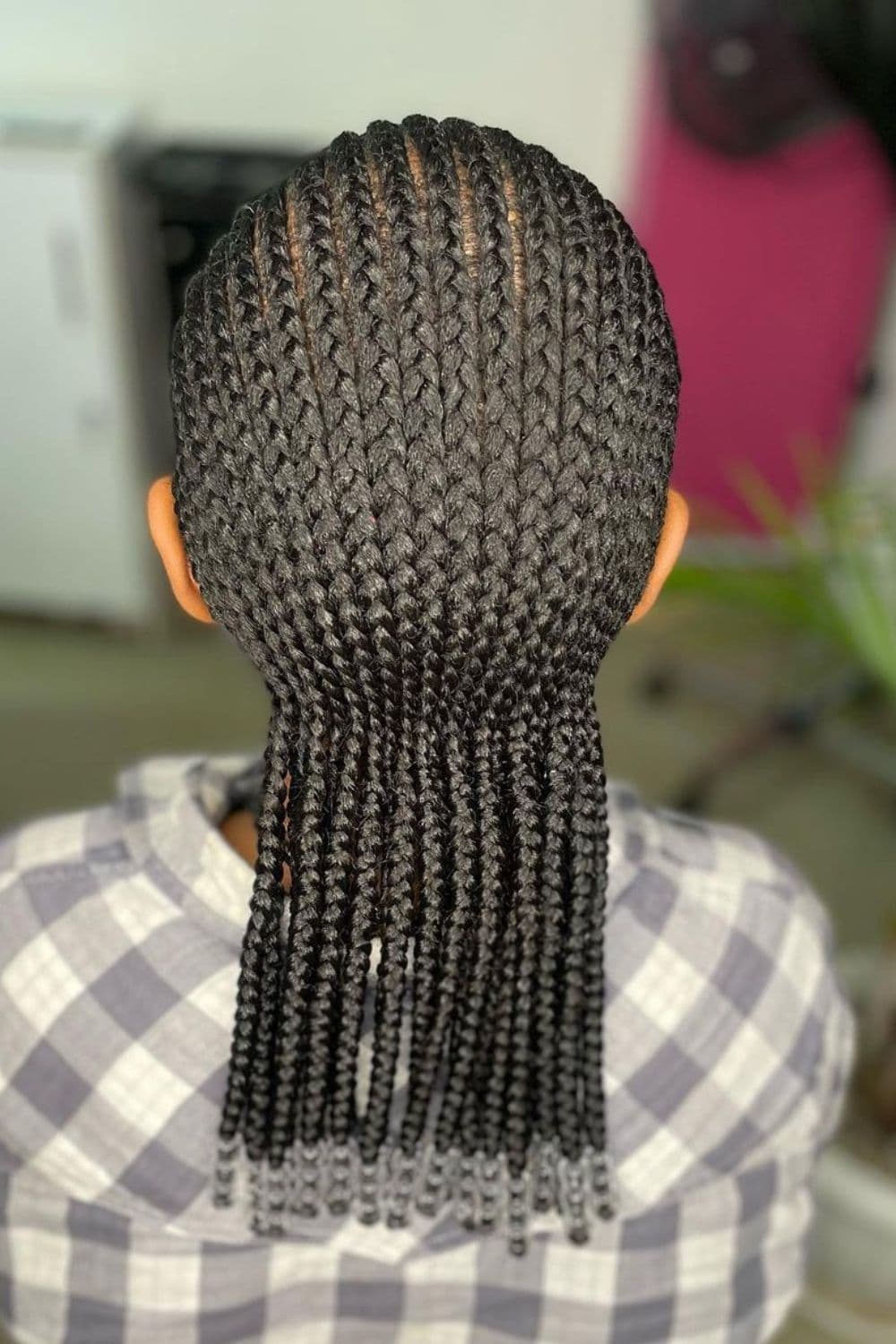 A person with black mid-length cornrows with beads.