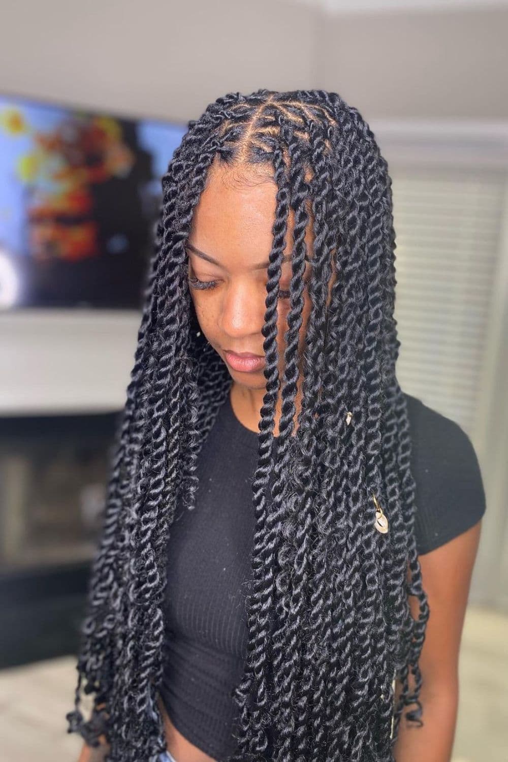 A woman with a black, middle part passion twists.