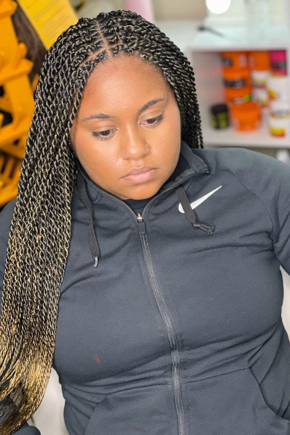 A woman wearing a black sweatshirt with middle-parted Senegalese twists.
