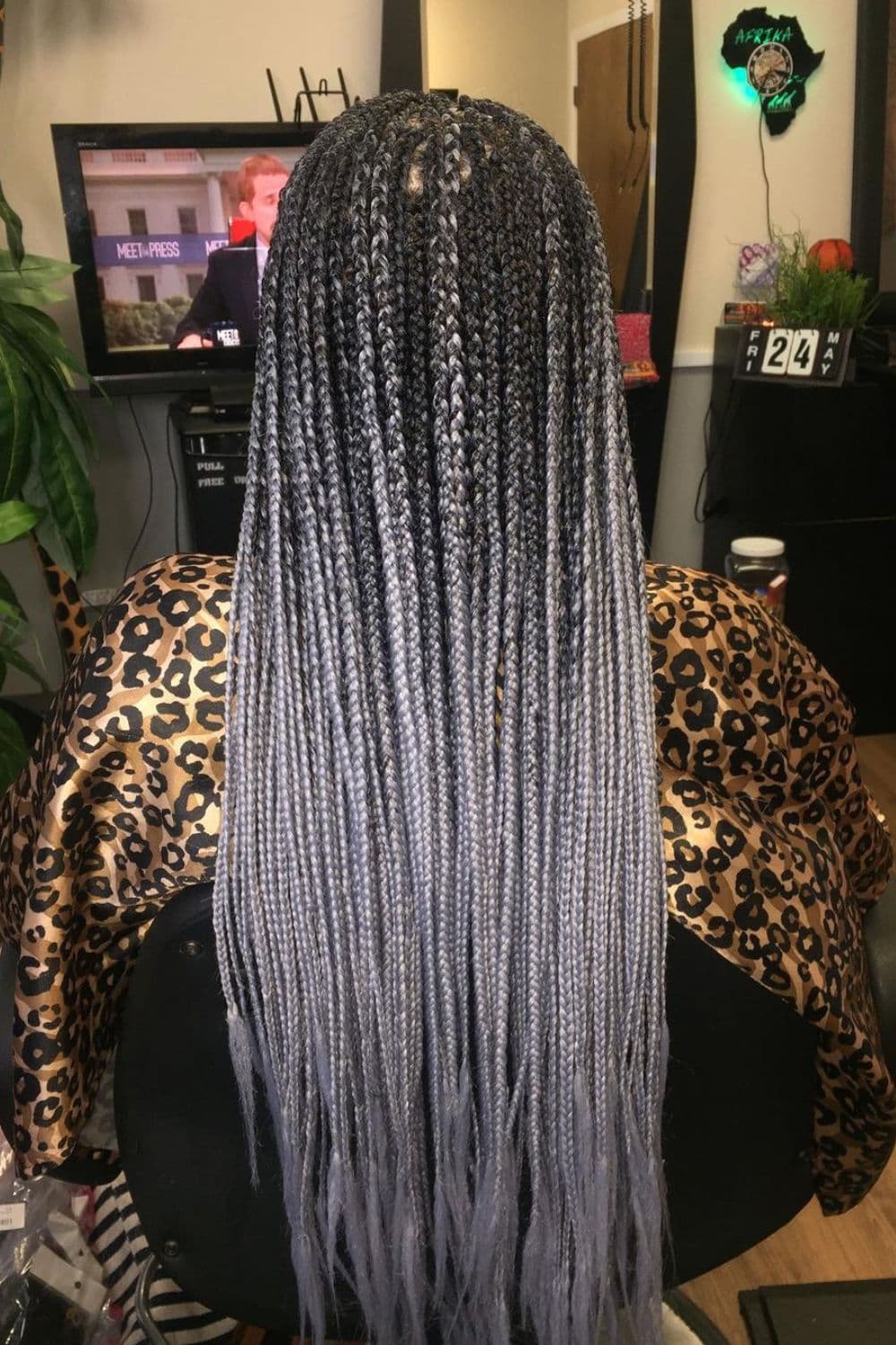 A woman sitting in a hair salon with black and gray mini braid ombre.
