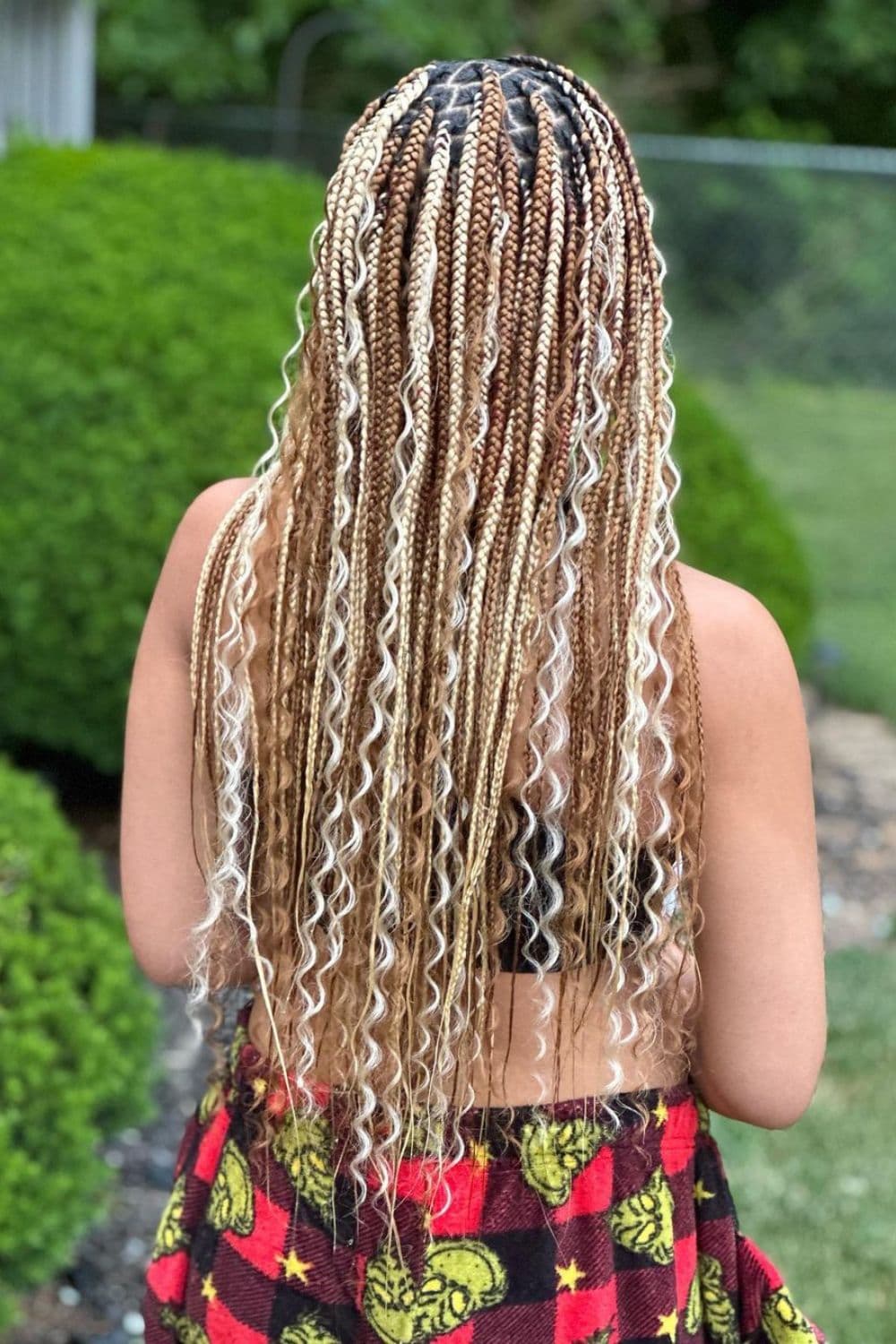 A woman standing outdoor with mixed blonde boho braids.