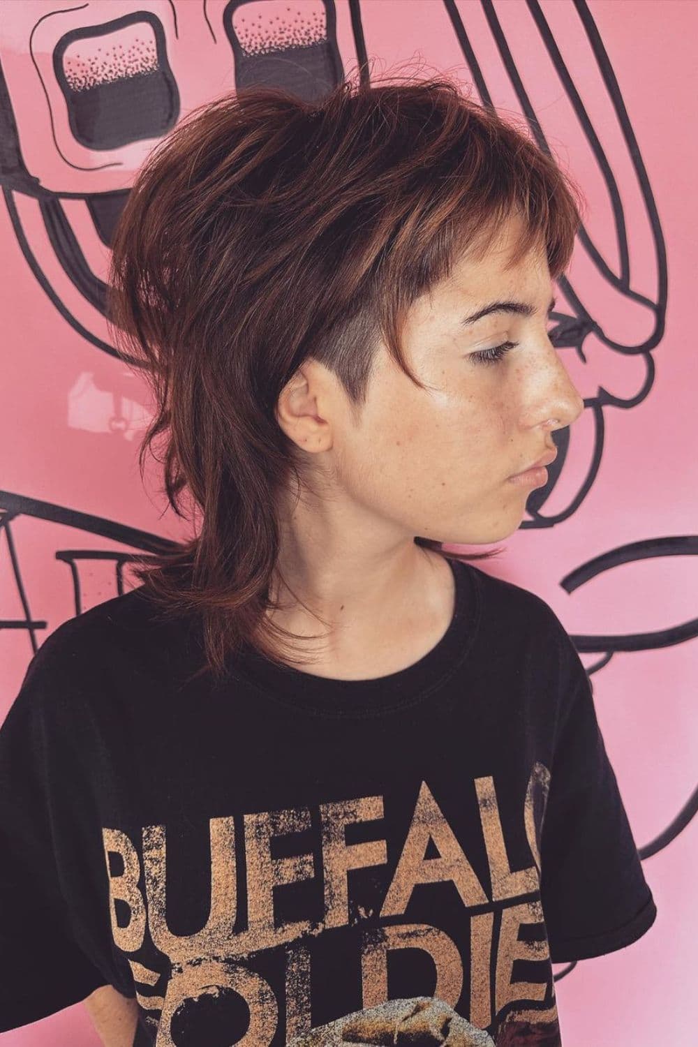 Side view of a woman with a brown mullet-style short wolf cut.