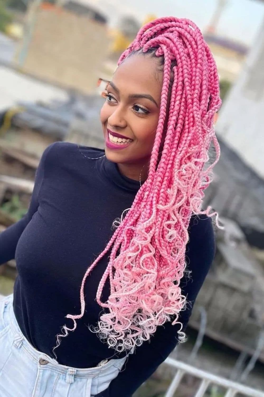 A woman with dark blue long sleeves with pink ombre box braids.