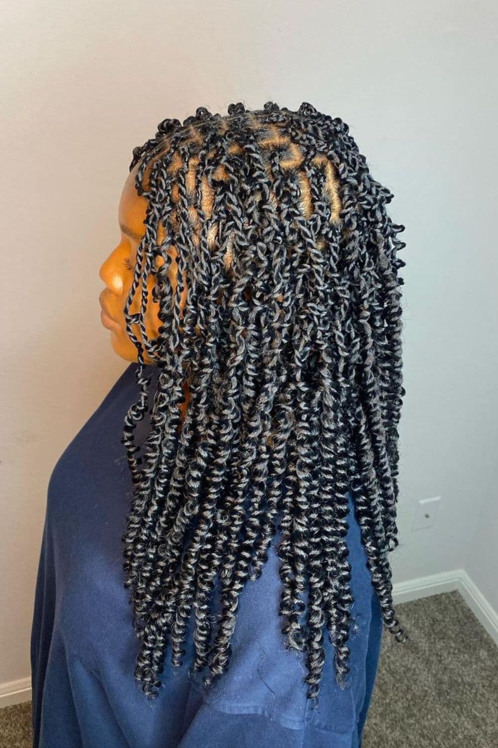 Side view of a woman wearing a blue sweater with black passion twists hairstyle.