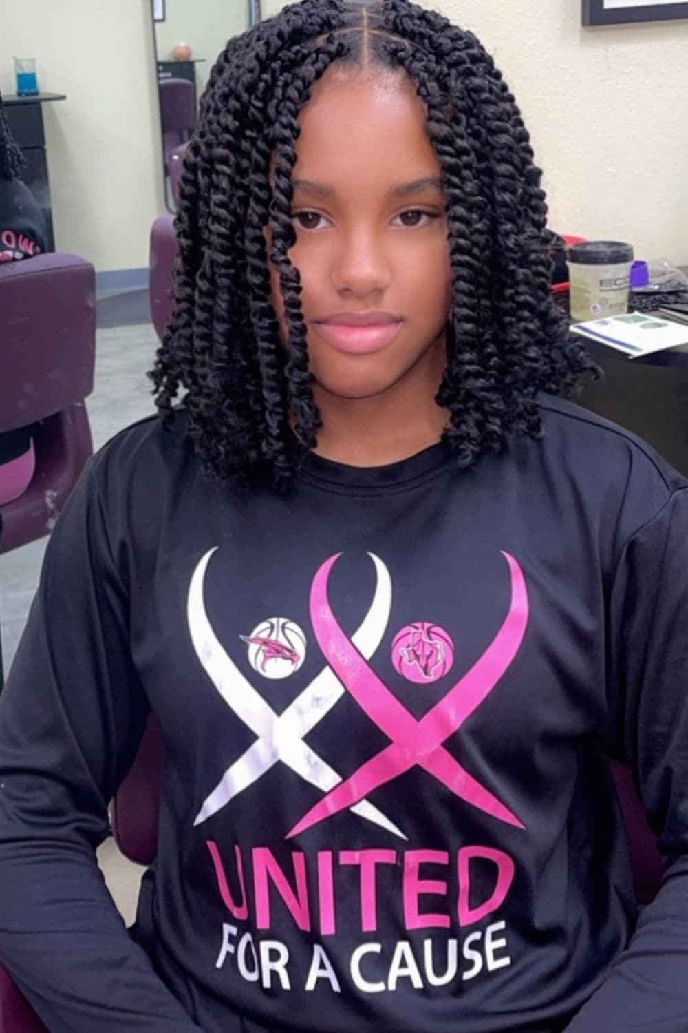 A girl wearing black long sleeves with a black passion twists bob.