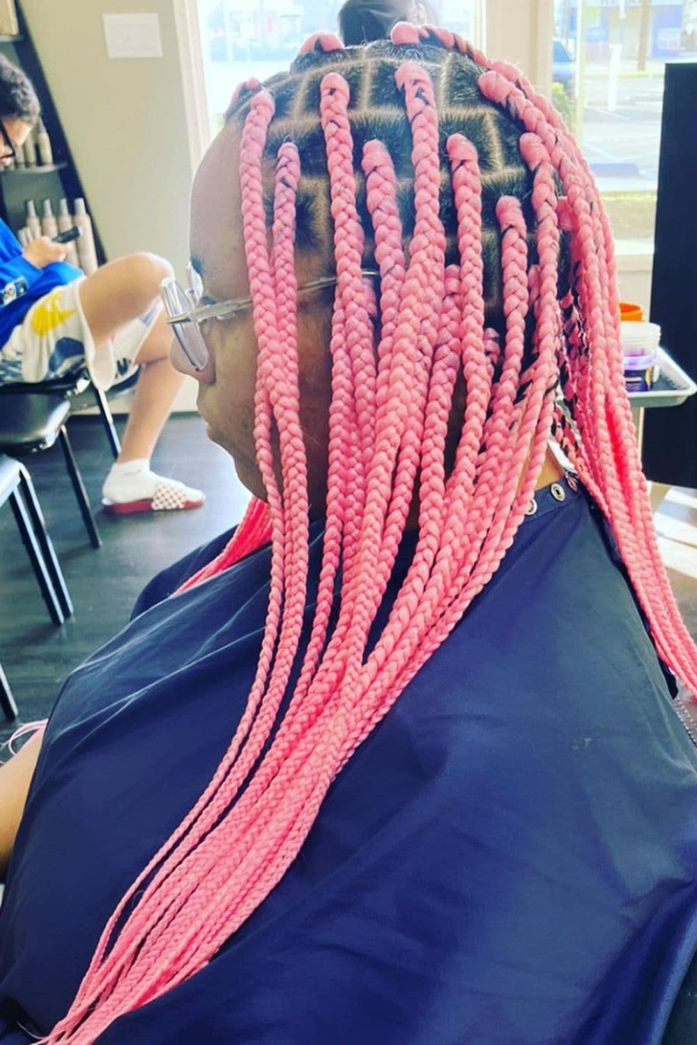 Side view of a woman with pastel pink braids.