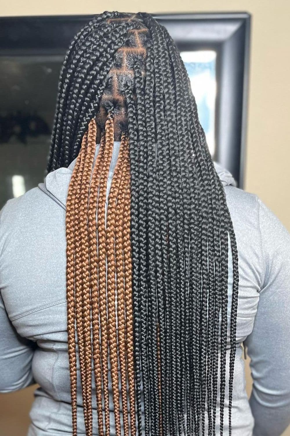 Back of a woman with black and brown peekaboo medium knotless braids.