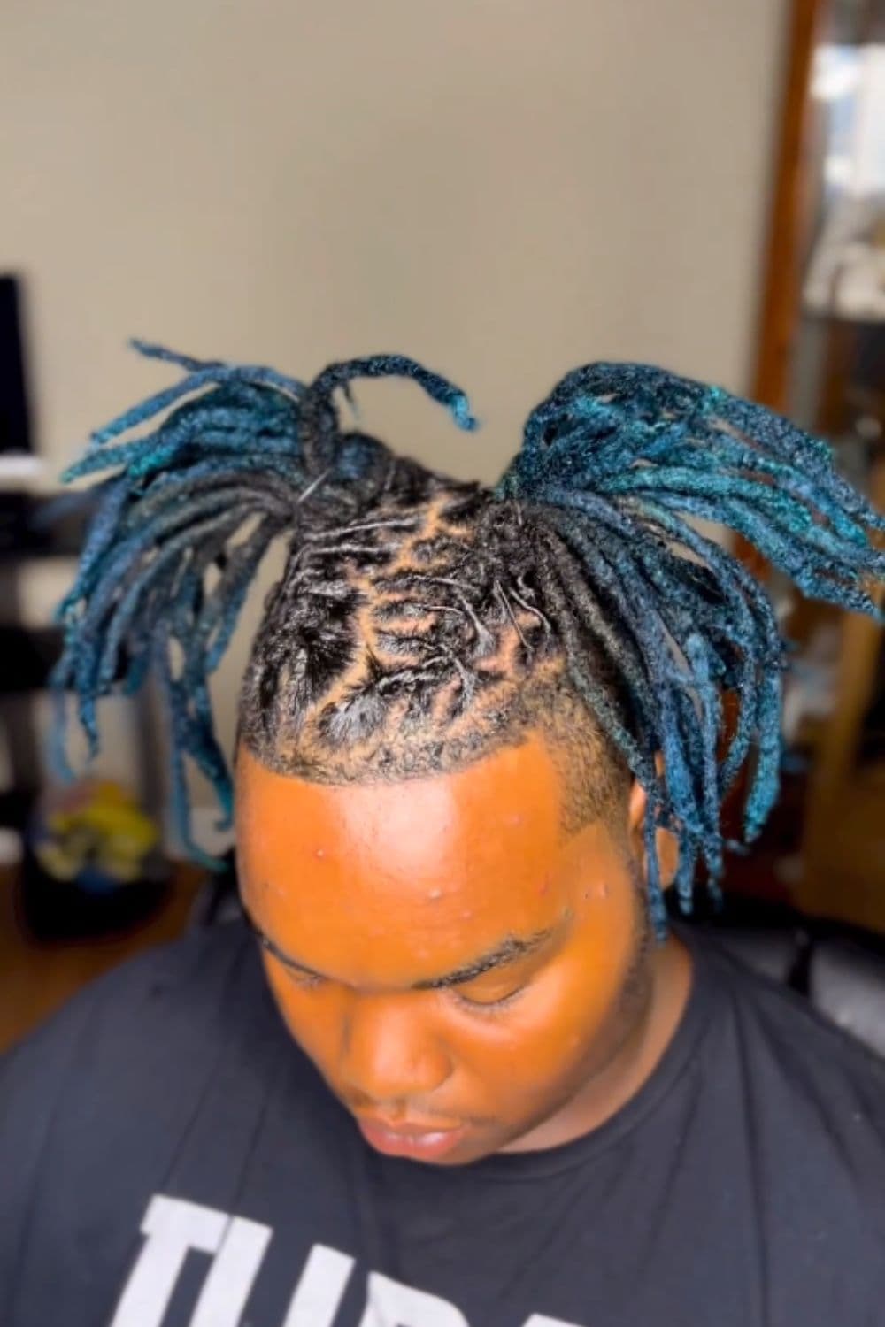 A man with blue and black pig tail comb twist.