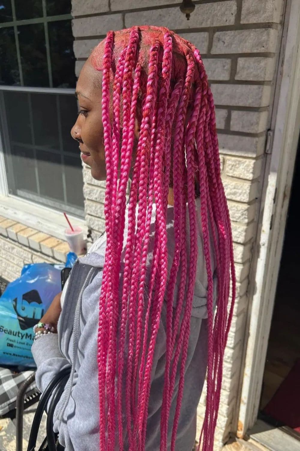 Side view of a woman with pink lemonade braids.
