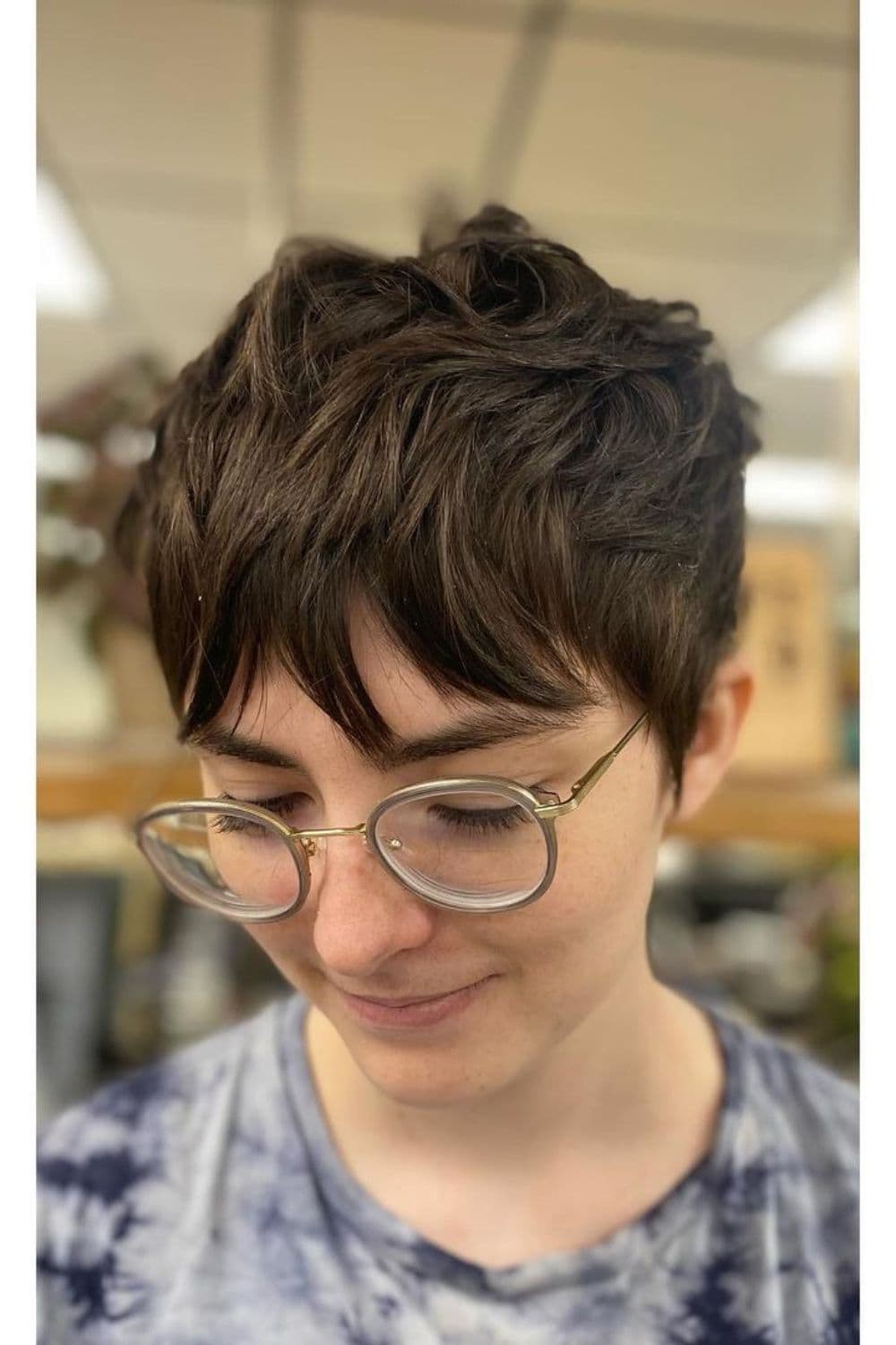 A woman wearing eyeglasses with pixie cut with wavy bangs.