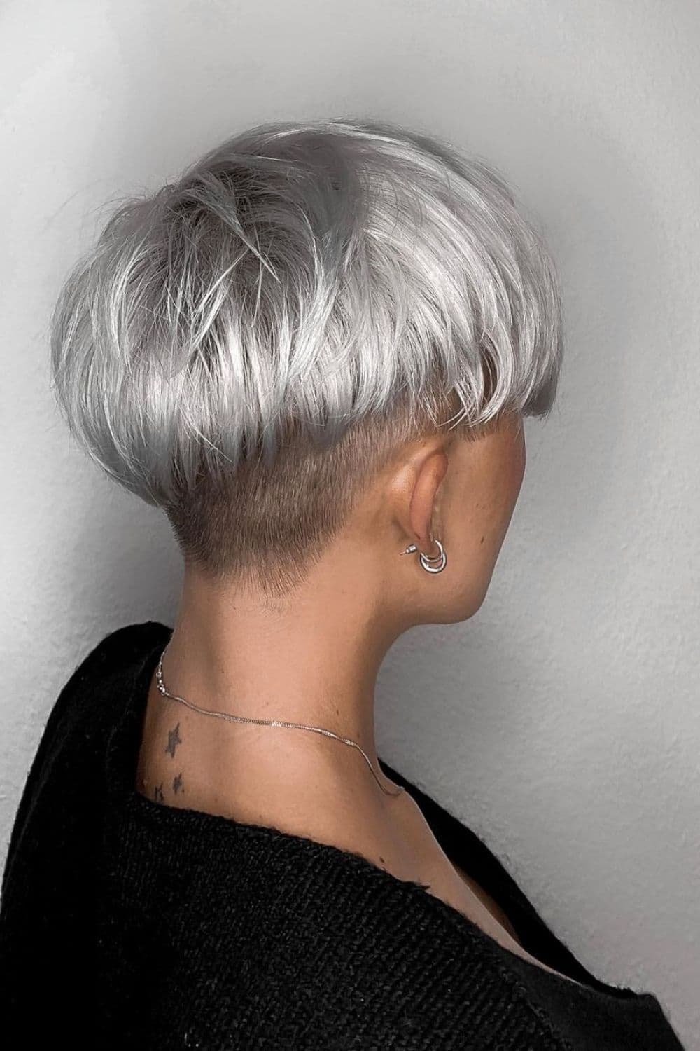 A woman with gray wavy pixie with shaved neck.