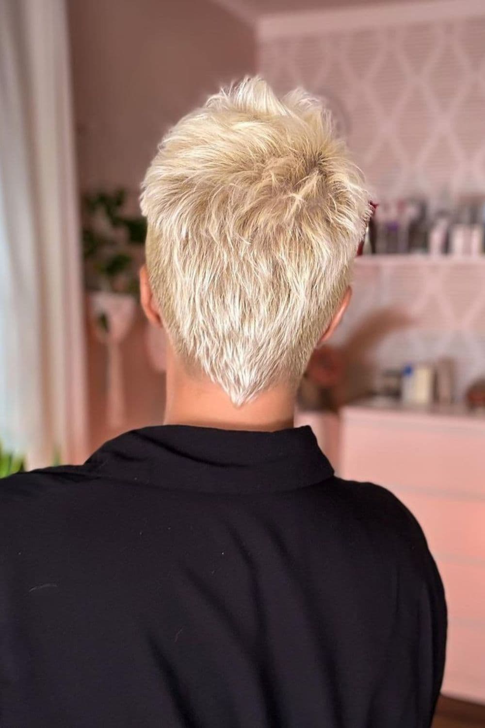 A woman's back with blonde wavy pixie with v-cut nape.