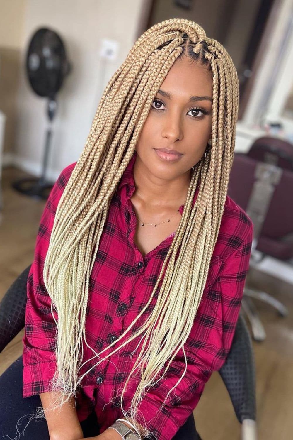 A woman wearing red plaid long sleeves with platinum blonde box braids.