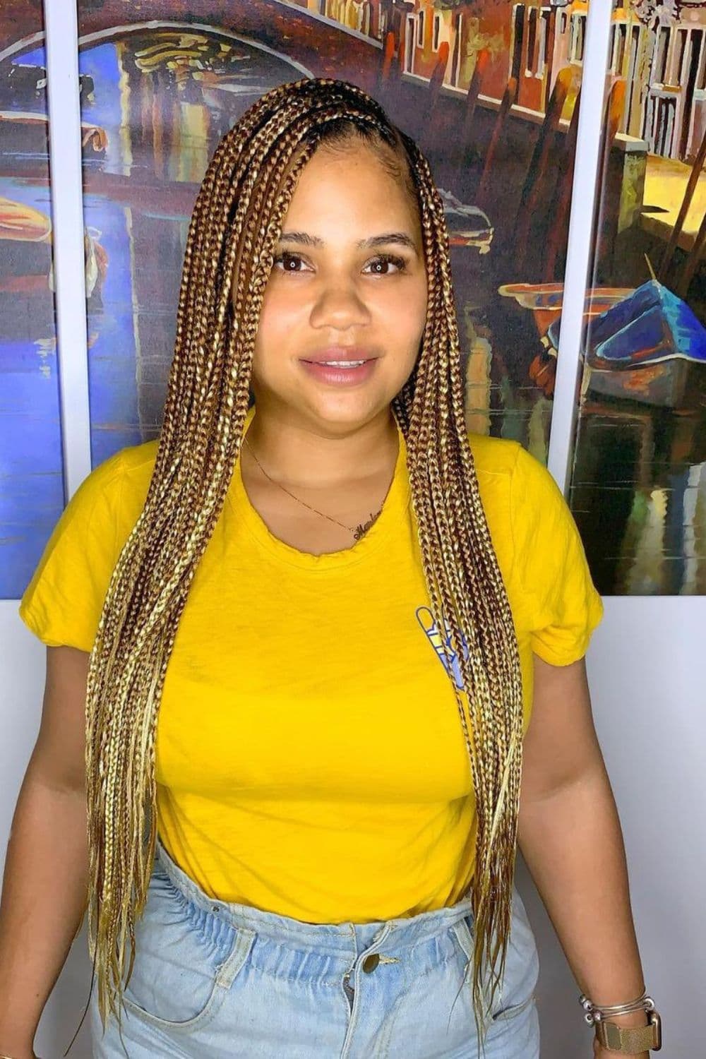 A woman wearing a yellow t-shirt with platinum blonde mixed knotless braids.